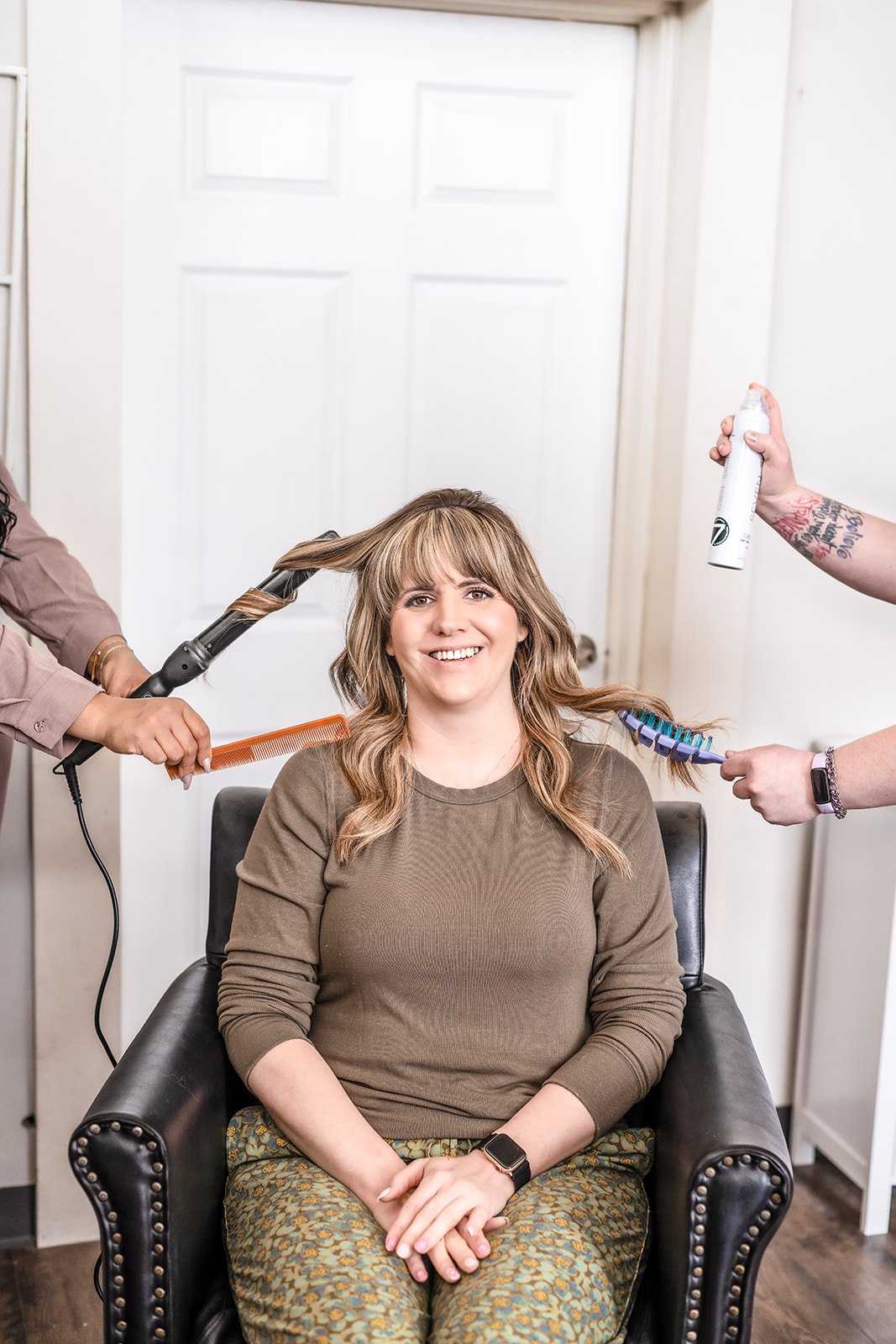 A guest at A Shade of Vintage being styled by the team with curling iron, comb, brush, and finishing spray